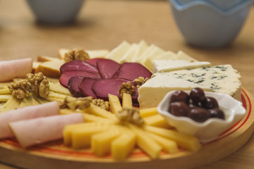 Cheese Board over Wooden Table With smoked meat