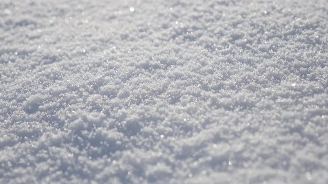Tilting on white crystals of first snow sparkling under sun 4K 2160p 30fps UltraHD footage - Frozen hill dunes of crystalline water shallow DOF 3840X2160 UHD slow tilt video 