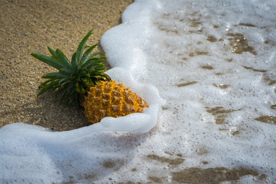 pineapple on the sand in waves