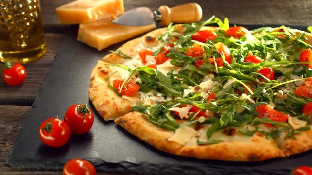 Pizza Caprese with arugula, cheese, yoghurt and cherry tomatoes closeup. Homemade delicious vegetarian pizza on wooden table. Dolly shot UHD 4K video footage. Ultra high definition 3840X2160