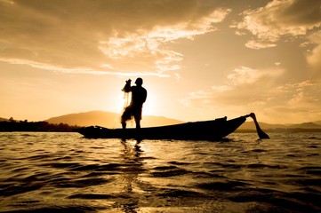 Silhouette of fisherman throwing fishing net in Thailand