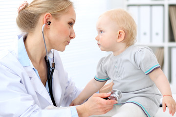 Pediatrician is taking care of baby in hospital. Little girl is being examine by doctor with stethoscope. Health care, medicine and help concept.