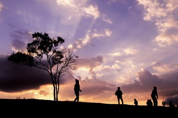 Silhouette of people walking on the hill with dramatic sky