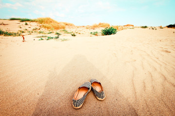 Fototapeta na wymiar Shadow of travelers And shoes on the sand