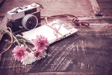 Vintage camera with bouquet of flowers on old wood background - concept of nostalgic and...
