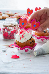 Vanilla cupcakes with chocolate chips and whipped cream frosting sprinkled with red colored sugar on the white background