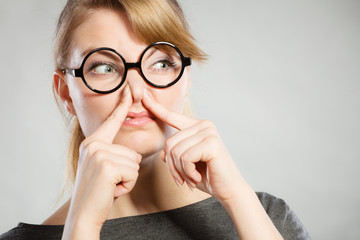 Girl pinches her nose because of stench stink.