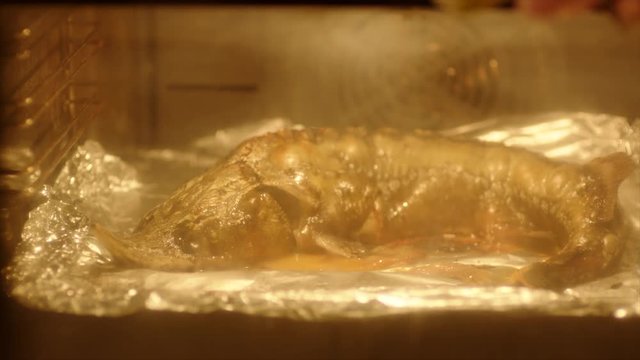 Housewife checking the readiness of sturgeon cooked in oven