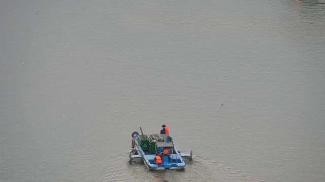 Unidentified janitor is working on river in Ho Chi Minh city. Ho Chi Minh is the biggest city in Viet Nam