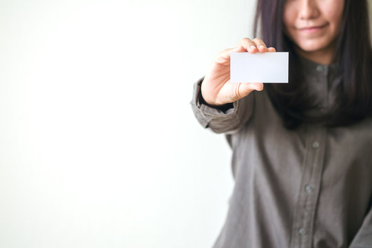 Minimal image of a beautiful woman holding and showing empty business card with white background and smiley face