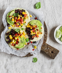 Spicy bean tacos with corn salsa and avocado  on a rustic cutting board on a dark background. Delicious vegetarian snack