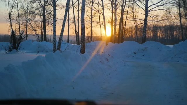 The car rides on winter road at sunset. Point of view