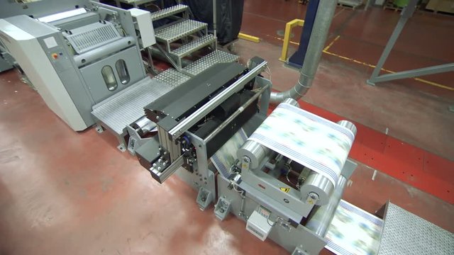 Crane shot of offset printing press working at high speed printing paper products