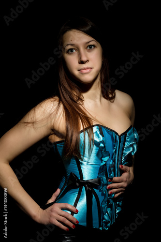 “portrait of sexy young woman in corset with lacing posing on a dark