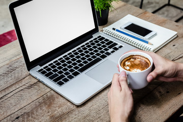 man hold coffee cup with laptop on wood table
