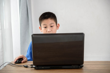 Fototapeta premium Young Asian boy using laptop technology at home. copyspace for t