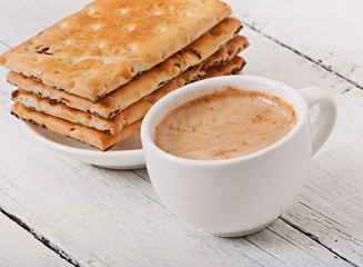 Cup of coffee and delicious baked cookies on old wooden background.