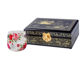 Picture of the wooden jewel-box with painting on wood and golden lock near decoupage glass isolated on white background. Painted pattern on closed box for bijouterie. Side view.