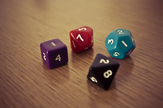 Colored polyhedral playing dice on wooden table