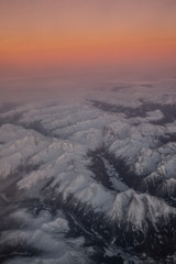 Fototapeta premium Aerial view of snowy mountains at sunset