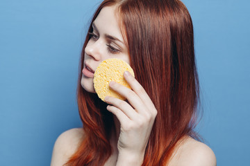 woman with yellow sponge on blue background, wipe face