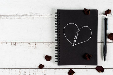 Red broken heart with dried rose petal and notebook