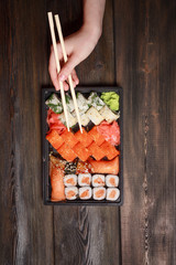 chopsticks and sushi with different fillings on a wooden table