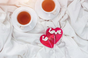 Fototapeta na wymiar Breakfast in bed in Valentines day. Cup of tea and sweet candies. Love or holiday concept