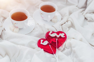 Breakfast in bed in Valentines day. Cup of tea and sweet candies. Love or holiday concept