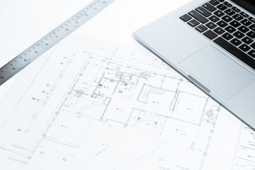 metal ruler and notebook over house construction blueprint with