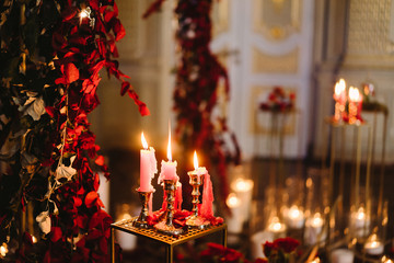 Decoration at reception in the evening. Vintage candlesticks and floral compositions in candles light.