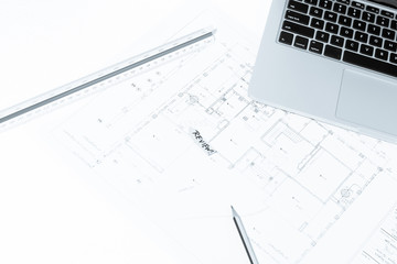 Pen, drawing rulers, and notebook over house construction bluepr