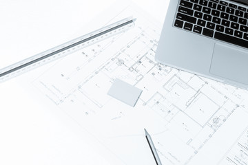Pen, drawing rulers, and notebook over house construction bluepr