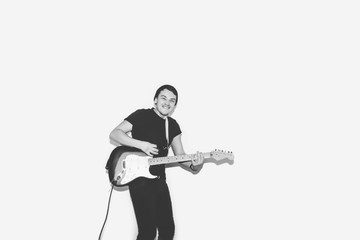 Naklejka premium Awesome crazy fashion young musician rock guitar player jumps with passion in studio. Stylish rocky emotional man. Black and white toned.