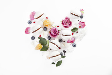 Meringue cookies in heart shape with flowers and blueberries