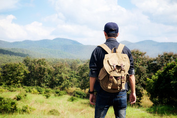 Hipster young man with backpack enjoying sunset on peak mountain. Tourist traveler on background valley landscape view mockup