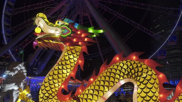 Big illuminated Chinese dragon figure festive and ferris wheel in Hong Kong at Night, 4k
