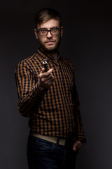 man with a beard wearing glasses on black background smoke Vape. large portrait of . electronic...