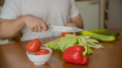 a man cooks in the kitchen he cuts vegetables