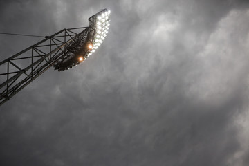Mast of floodlights against dark dramatic sky. Copy space in the sky. Slight noise due to high iso...