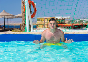 Young man standing at the gate in pool playing water polo