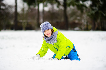 Fototapeta na wymiar The boy of school age plays snowballs in the winter park.