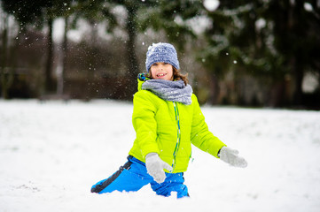 Fototapeta na wymiar The boy of school age plays snowballs in the winter park.