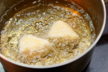 Deep fryer with pieces of breaded camembert