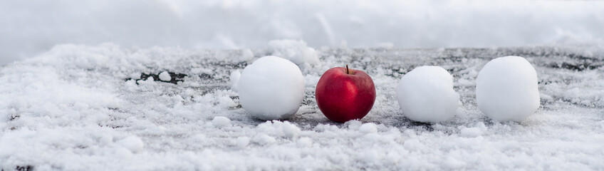 Red apple on the snow and throwing snowballs