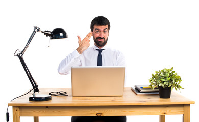 Businessman in his office making suicide gesture