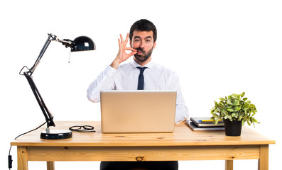 Businessman in his office making silence gesture