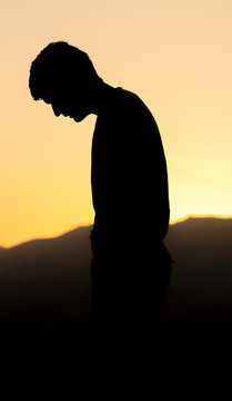 Silhouette of a man praying on the street in a beautiful landscape
