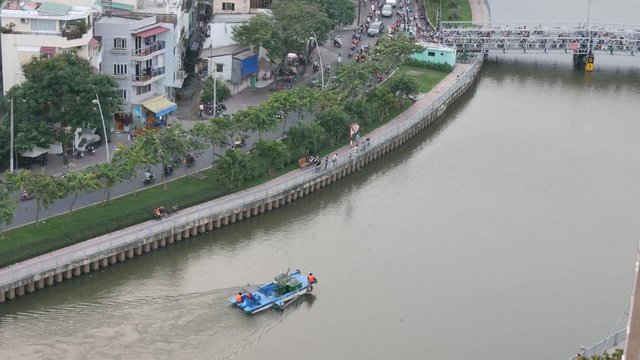 Unidentified janitor is working on river in Ho Chi Minh city. Ho Chi Minh is the biggest city in Viet Nam