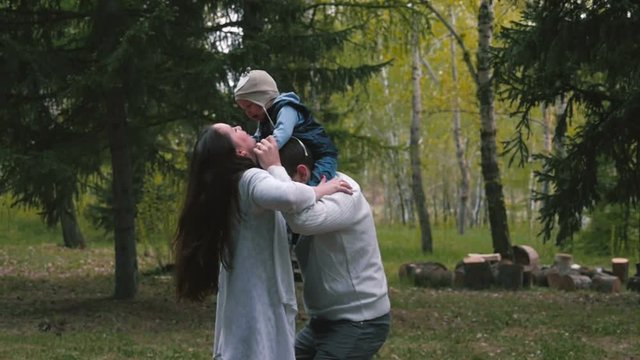 Family with a small child playing in the forest. Slow motion